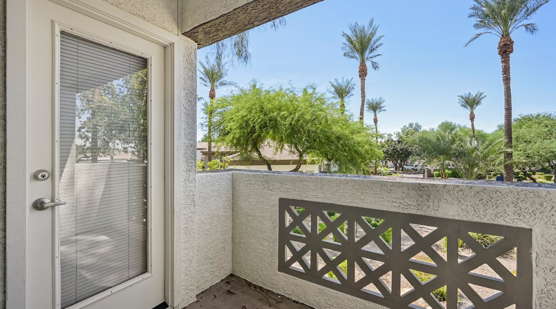a white door with a glass window and a white wall with trees and blue sky