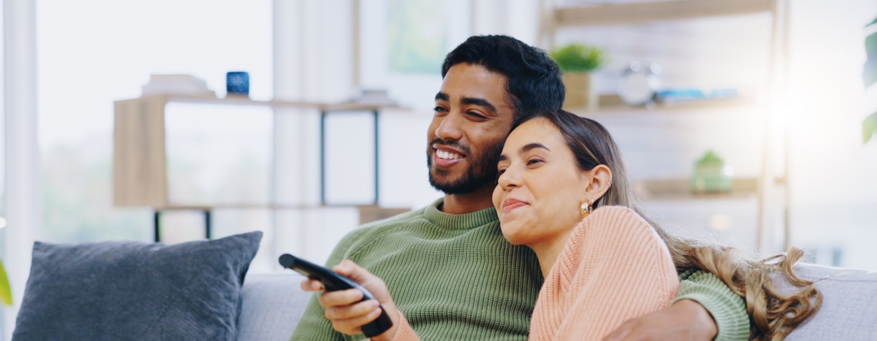 a man and woman looking at a tv on a couch