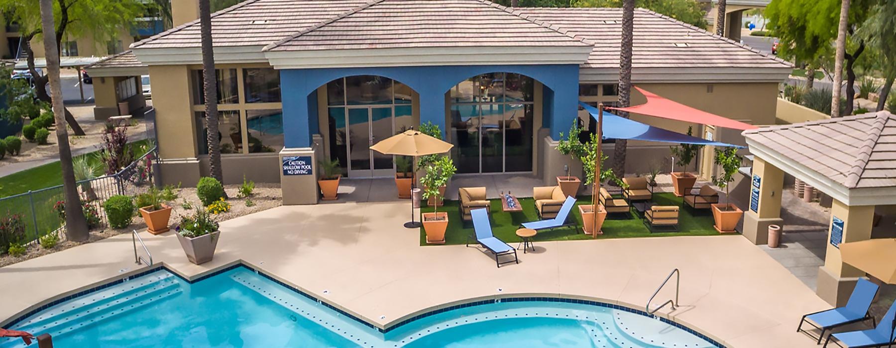 a swimming pool with chairs and umbrellas next to a building